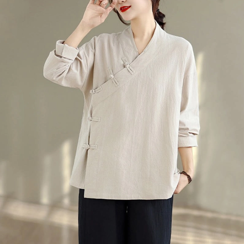 Upper body close-up of women's zen meditation yoga uniform top showing v-neck cross collar with frog button closure in beige