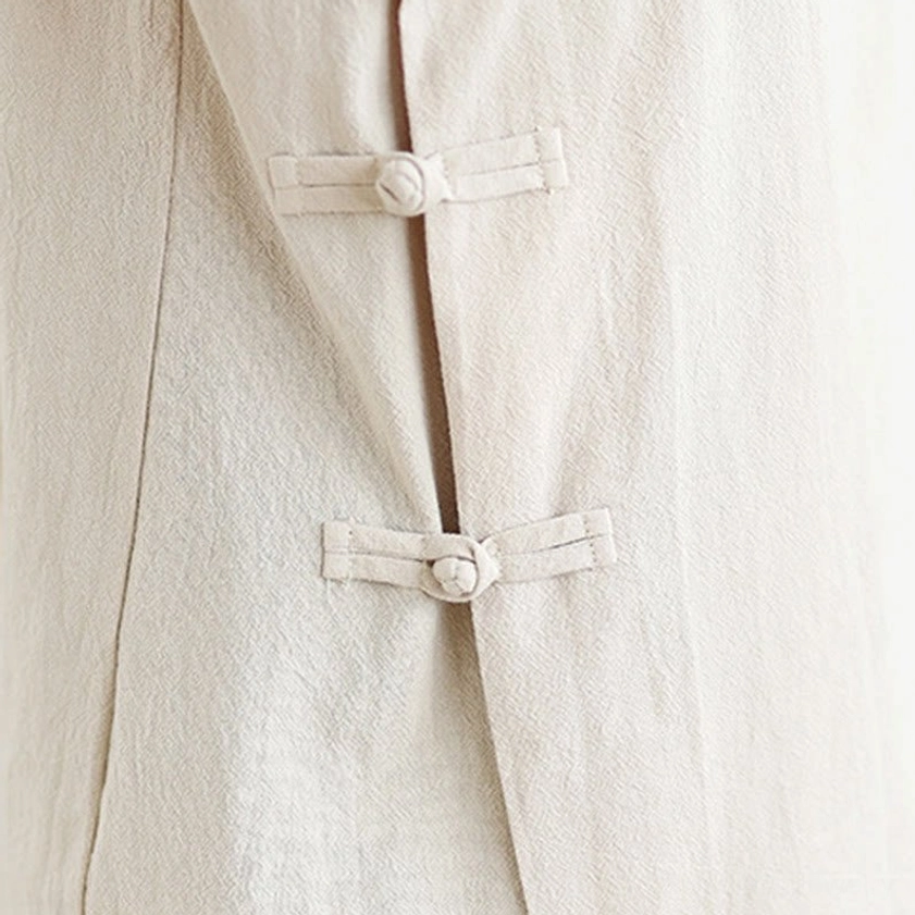 Side view close-up of fabric frog button closure on zen meditation yoga uniform top in beige linen cotton blend