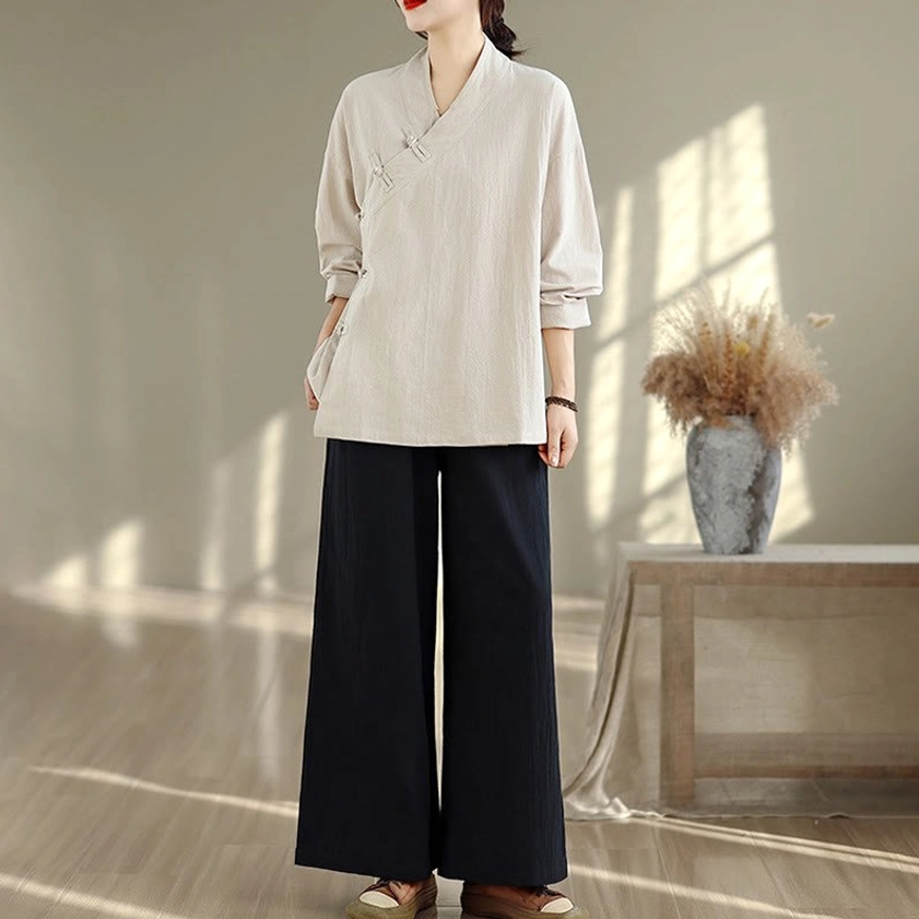 Three-quarter front view of zen meditation yoga set showing woman in beige top with black wide-leg pants, hand on hip