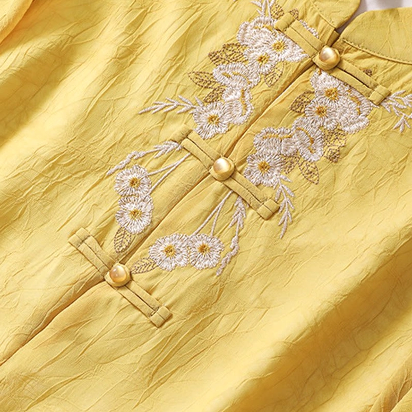 Front close-up of meditation tunic showing detailed traditional frog closures, golden button details, and delicate white floral embroidery work