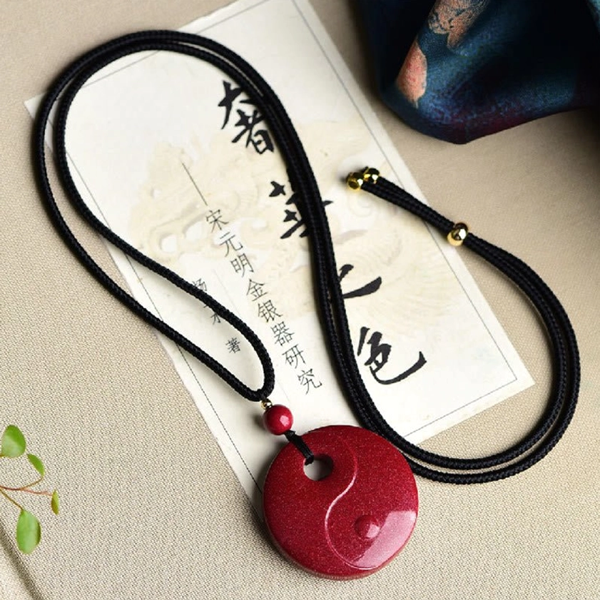 Zodiac sign cinnabar Buddhist pendant showing detailed carved animal design on rectangular wine-red stone surface