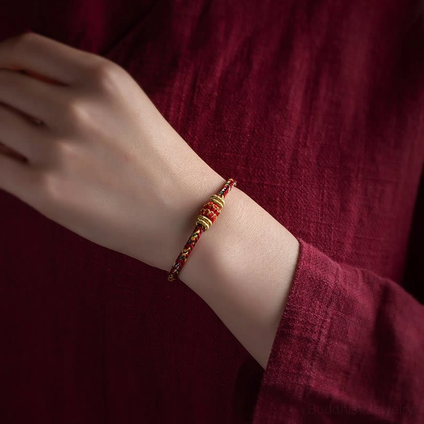 Handmade braided buddhist zodiac bracelet worn on wrist showing red and gold woven design