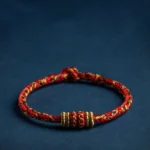 Handmade red braided buddhist zodiac natal buddha string bracelet with gold decorative knots, flat lay view