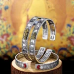 Complete collection of zodiac natal buddha protection bracelets in sterling silver with gold guardian deity figures displayed on wooden stand with Buddhist background