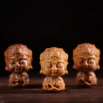 Three carved zodiac natal Buddha figurines in green sandalwood wood displaying distinct chibi facial features and lotus engravings