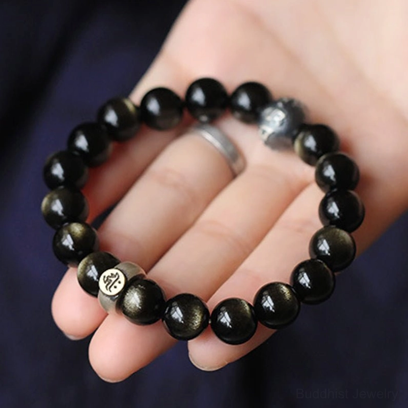 Hand holding obsidian zodiac bracelet with sterling silver decorative beads