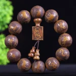 Hand-carved Buddhist zodiac wooden bracelet with 12 beads showing zodiac animals carved details, displayed with green foliage backdrop