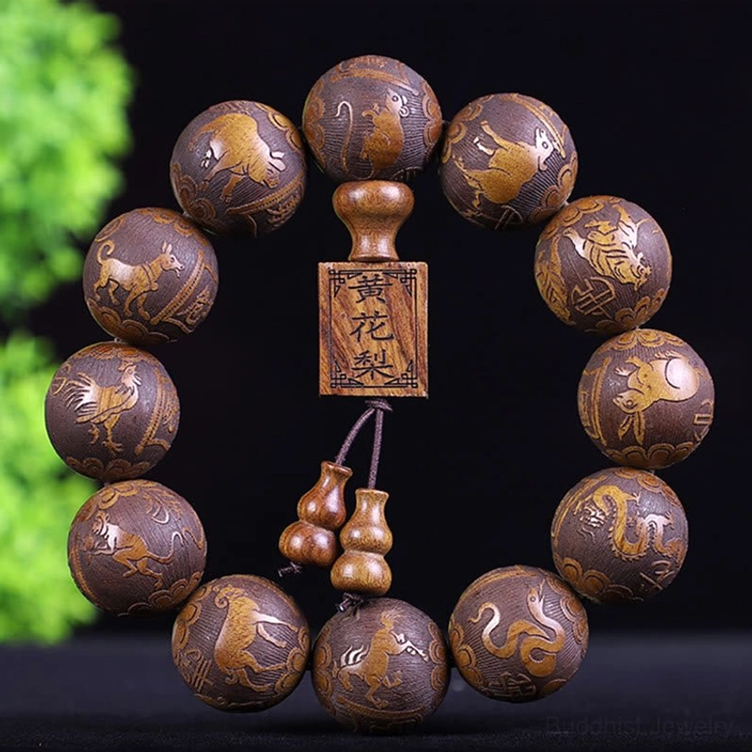 Hand-carved Buddhist zodiac wooden bracelet with 12 beads showing zodiac animals carved details, displayed with green foliage backdrop